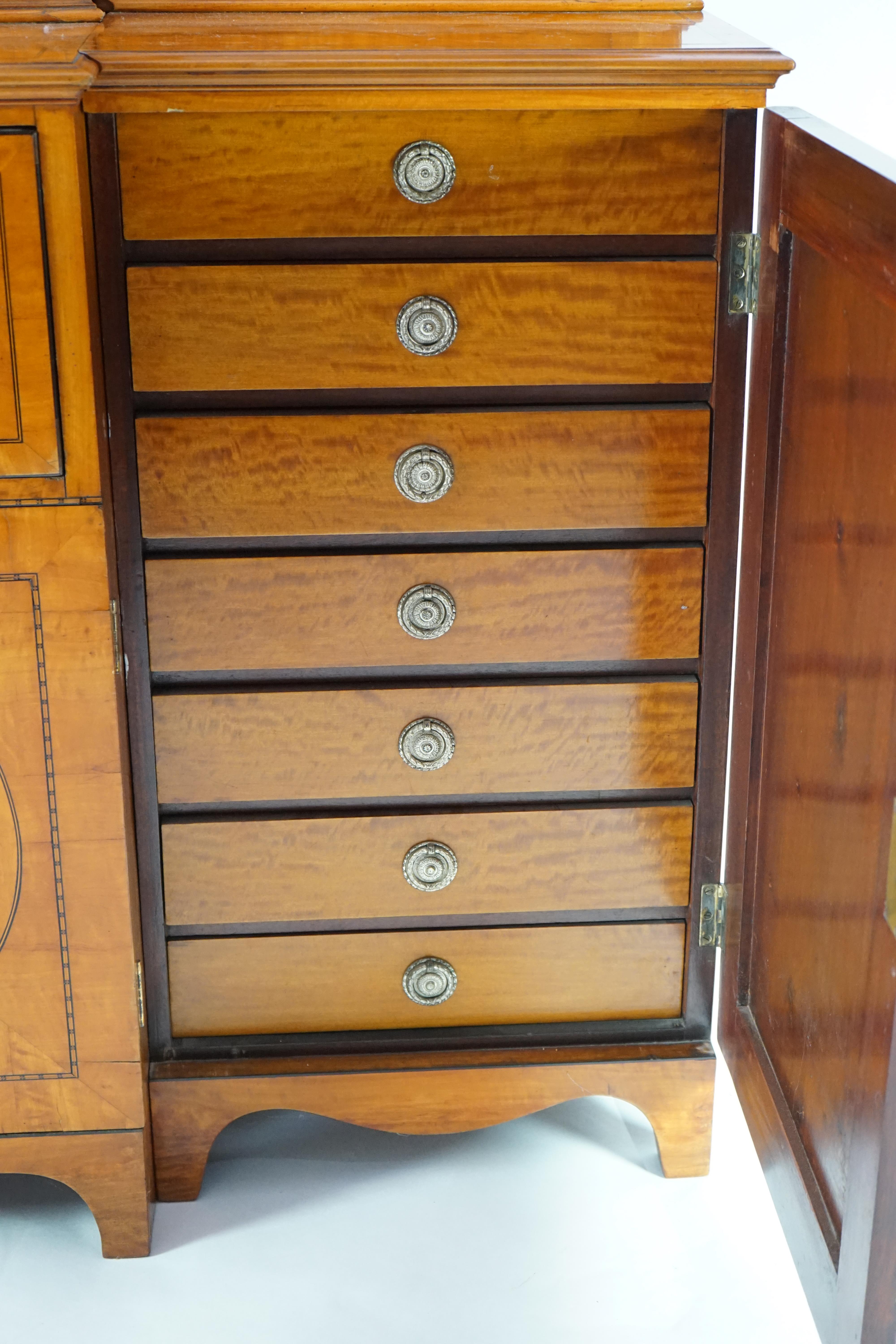 A Sheraton revival ebony strung satinwood breakfront secretaire bookcase